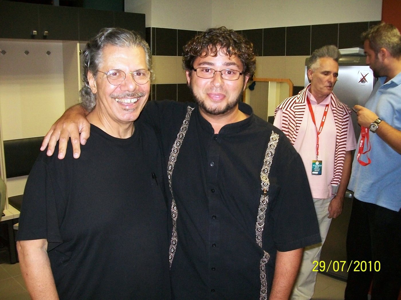 Yan Kayary con Chick Corea, abrazados, de pie en un pasillo con otras personas al fondo