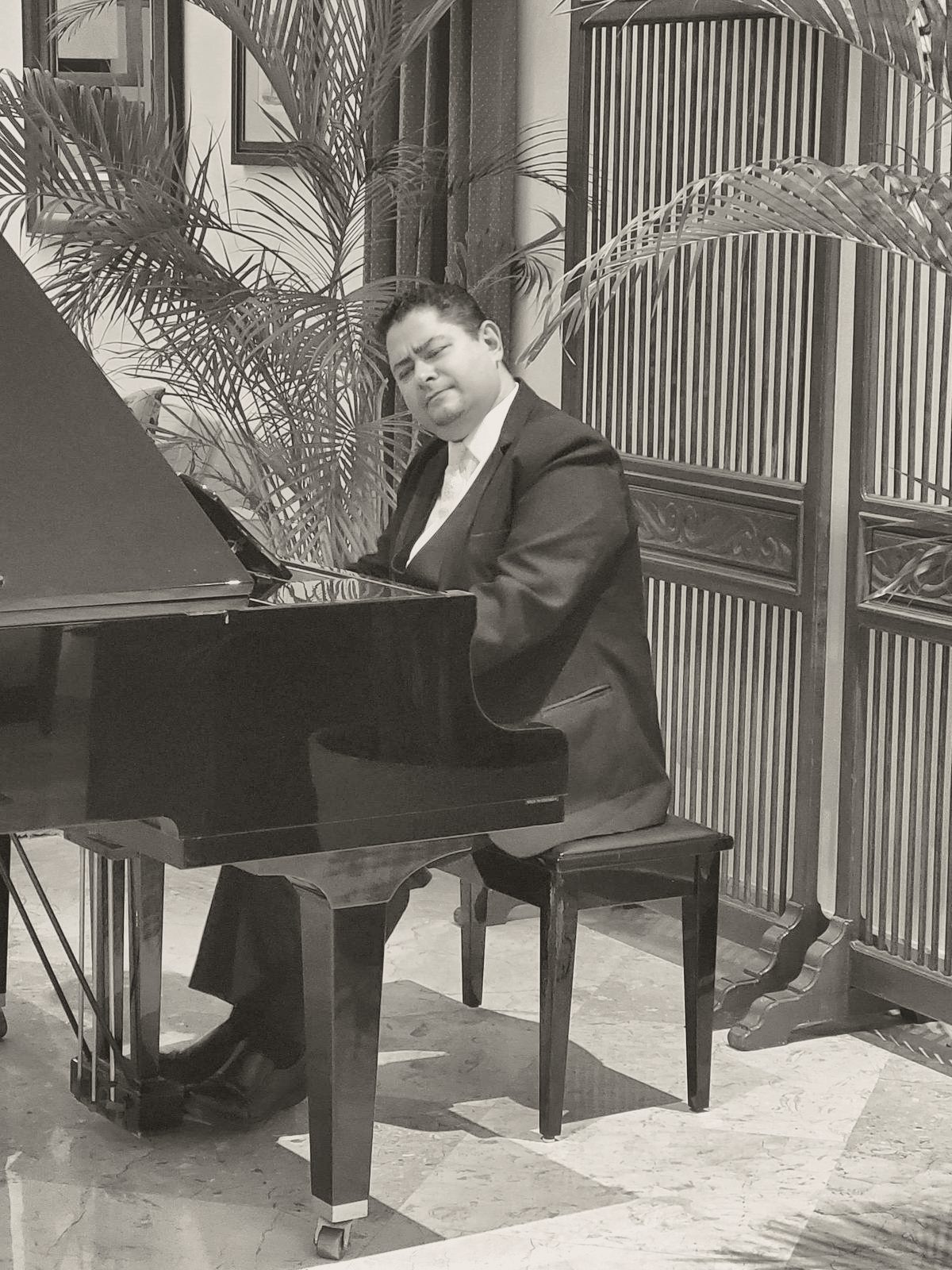 Yan Kayary al piano de cola, en blanco y negro, entre celosías
