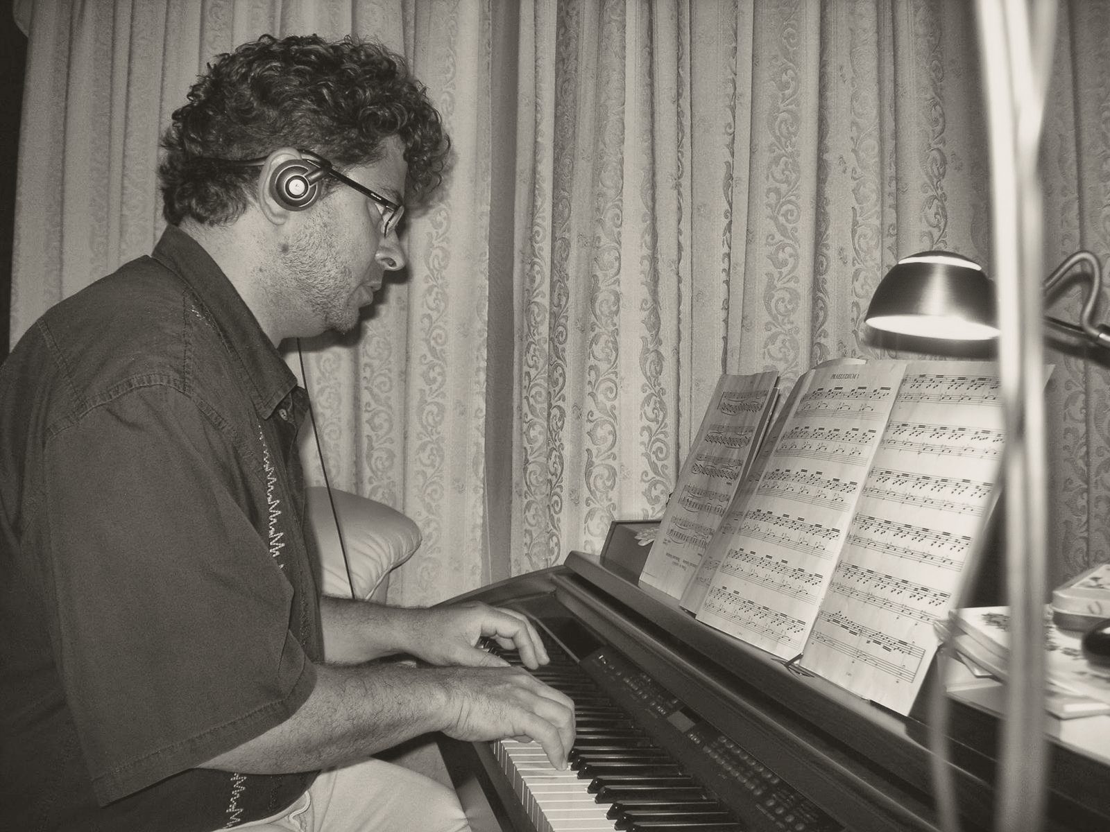 Yan Kayary con auriculares, leyendo una partitura al piano
